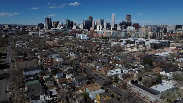 Downtown residential contrast shows Denver skylines office towers rising beyond Lincoln Park as West 9th Avenue housing blocks lead toward metropolitan. Mixed roofing colors, bright facades, CO