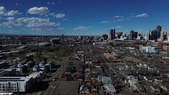 City grid progression frames Denver in distance as Lincoln Park blocks transition toward community density along central corridor. Sunlit roofs scattered trees, apartment complex, townhomes, CO