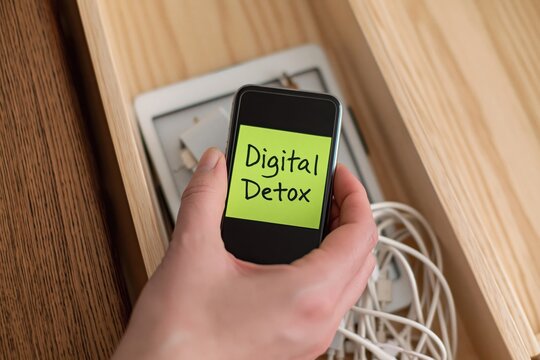 Hand placing smartphone in wooden box for digital detox and wellness