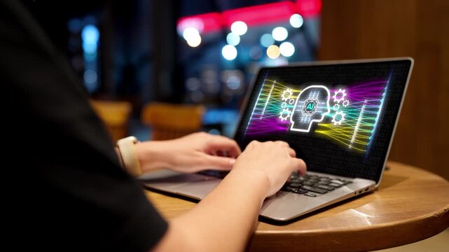Close up of a programmer typing on a laptop keyboard with a futuristic artificial intelligence AI brain network graphic on the screen in a cafe at night.