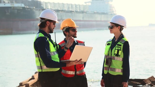 Team male and female engineers in uniform safety equipment stand surveying the area infrastructure development projects including the construction deep sea distribution port land bridge and shipyard.
