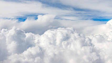 Fototapeta premium Fluffy clouds cover the sky during a sunny day in the afternoon with blue peeking through