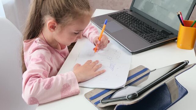 Hybrid learning child studying at home desk with online lesson