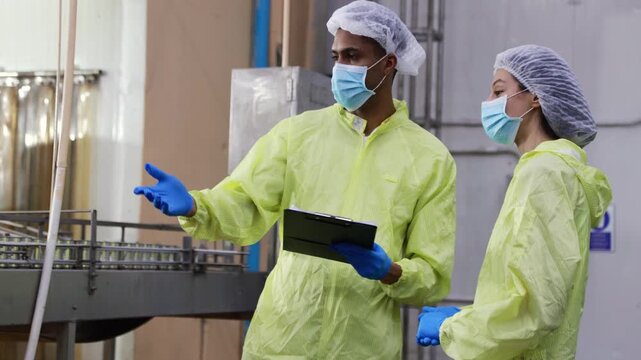 Supervisory team wearing PPE meticulously inspects the mackerel or sardine production line from canning to tomato sauce filling on conveyor belts in industrial seafood processing plants.