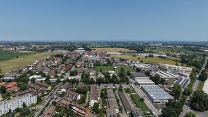 Obraz premium Italian Suburban Landscape: An aerial view showcases a sprawling Italian suburban landscape under a clear blue sky, featuring residential homes, Mombretto, Milan, Italy