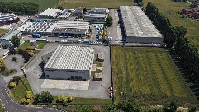 Industrial Park Aerial View: An aerial perspective showcases a sprawling industrial park with various factory buildings, warehouses, and an adjacent field under a clear sky.