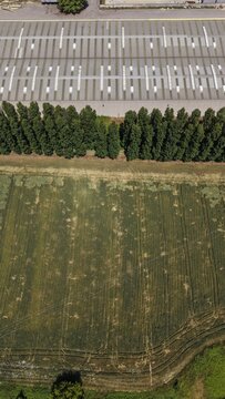 Industrial Landscape and Farmland: An aerial view captures a stark contrast between a large industrial complex with rows of parking spaces and a lush green agricultural field.