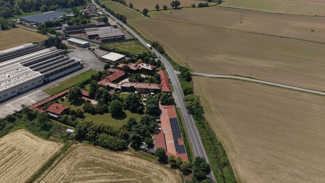 Rural Landscape with Industrial Elements: An aerial view showcases a rural landscape where fields and residential areas meet industrial buildings, bisected by a road.