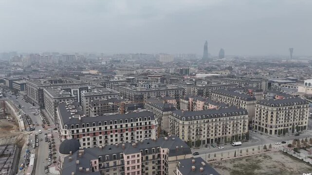 panoramic aerial cityscape of modern residential buildings and urban development in baku azerbaijan under cloudy hazy sky. Contemporary architecture and expanding city infrastructure.