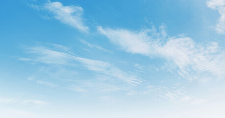 Obraz premium Soft clouds drift across a serene, light blue sky