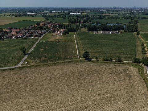 Rural Landscape: An aerial view captures a serene countryside scene, showcasing a patchwork of agricultural fields, a small village, San Martino Olearo, Milan, Italy
