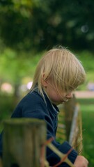 Fototapeta premium Young child looks over wooden barrier with concentration