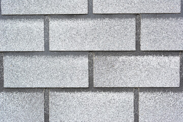Fototapeta premium Close-up of gray asphalt roof shingles with granular texture