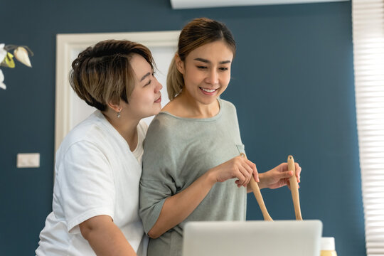 Asian LGBT lesbian couples spending sweet time cooking food together at home, pride month concept