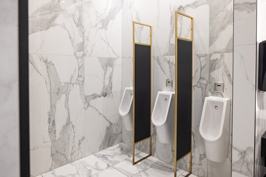 Row of modern white urinals in luxury marble public restroom
