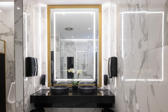 Luxury public restroom interior with marble walls and illuminated mirror