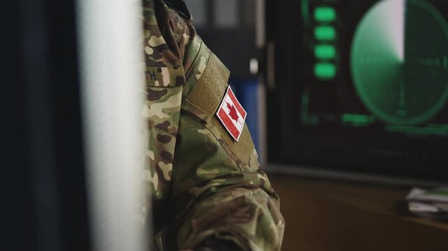 Canadian army officer controlling air mission operations on computer in office