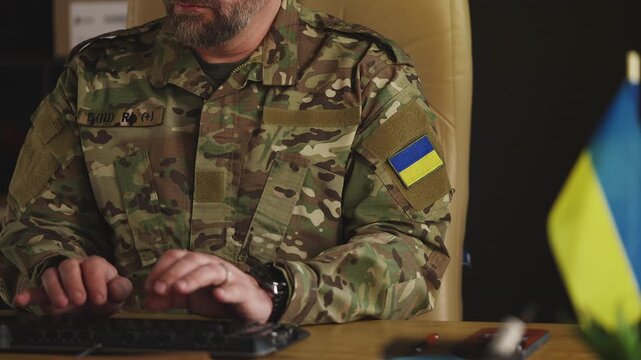 Ukrainian army officer working on defense strategy using computer in office