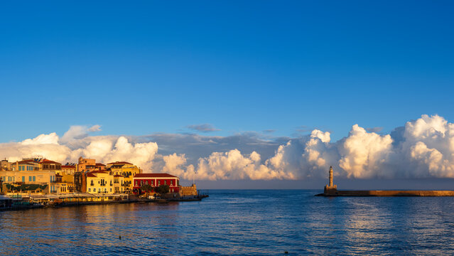 Port and Lighthouse of Chania, Crete in Greece early in the morning with sun lightening the clouds in the distance