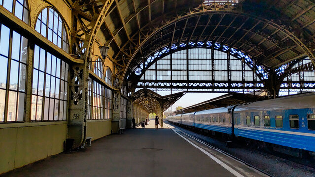 Vitebsk railway station in Saint Petersburg features a spacious platform with a blue train. The architecture includes large windows and a high arched roof.