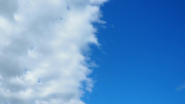The sky with blue and gray clouds. The camera focuses on the clouds as they change shape and position over time. The setting is open with a clear view.