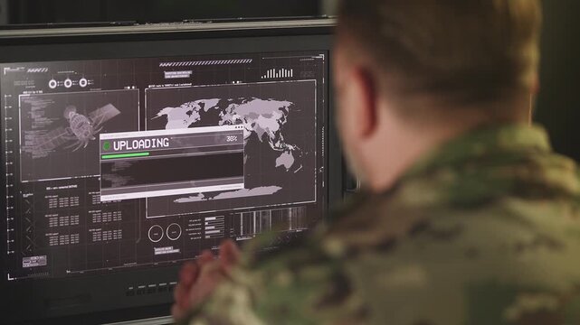 Middle-aged service member uploading satellite intelligence data on computer