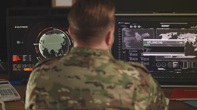 Back view of army officer working with surveillance systems and uploading data