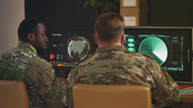 Two army officers discussing military operation while monitoring satellite data