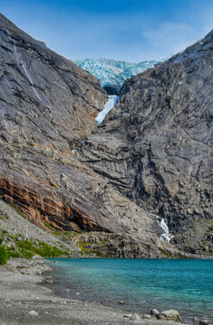 Blue Ice of Briksdalsbreen Glacier Over Rocky Mountain Lake in Norway