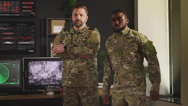 Two military officers standing in command center with satellite data screens
