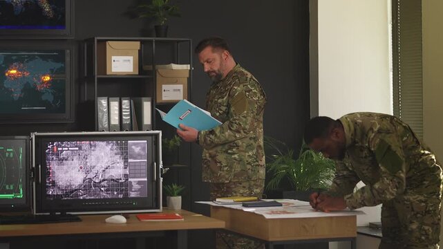 Two officers developing military strategy using maps and intelligence reports