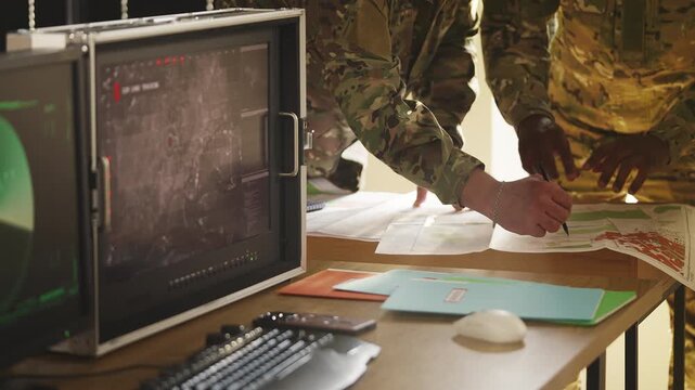 Two soldiers preparing operation plan using maps and surveillance data