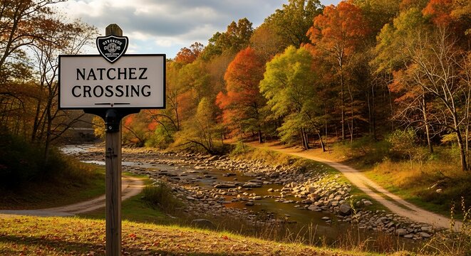 Scenic autumnal landscape with a sign for NATCHEZ CROSSING, dirt roads, and a rocky stream