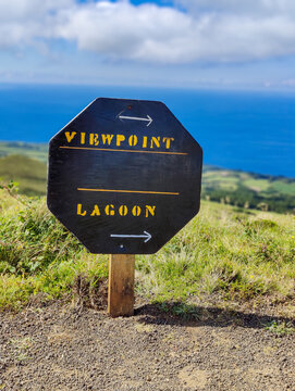 Wooden hiking trail signpost pointing to viewpoint and lagoon against blue ocean in the Azores