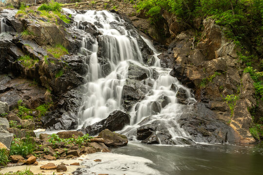 Smooth flowing waterfall at Antietam Lake Falls in Reading, PA, captured with long exposure among rocks and lush greenery.