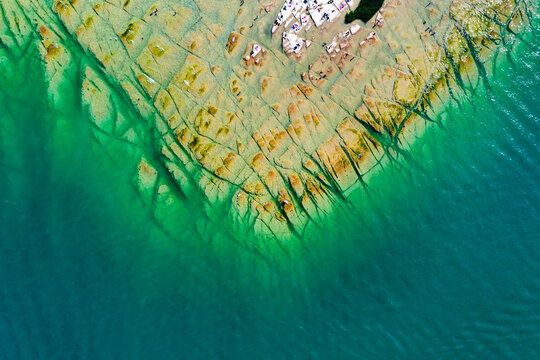 Aerial view of Jamaica Beach featuring flat rock formations and crystal clear turquoise water in Sirmione, Lombardia, Italy.