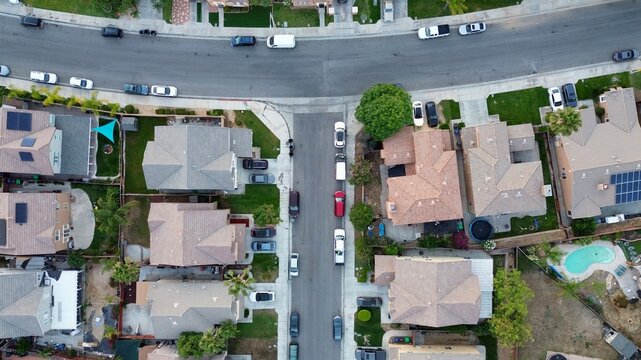 Aerial top down view of a suburban residential neighborhood street with houses and parked cars in Perris, California