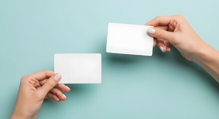 Obraz premium Two Hands Holding Blank White Cards Against a Light Blue Background