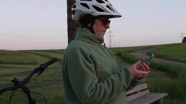 Woman cyclist checking map on smartphone during evening e-bike ride 