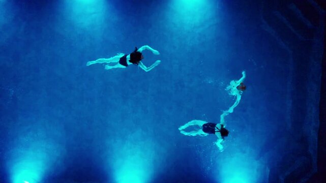 Overhead shot of female friends enjoying quiet time in swimming pool. Stock footage shows peaceful relaxation, evening recreation, and serene spa style ambiance