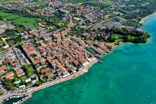 Aerial view of the historic town of Lazise on the shores of Lake Garda featuring the Scaligero Castle, terracotta rooftops, and turquoise waters Italy.