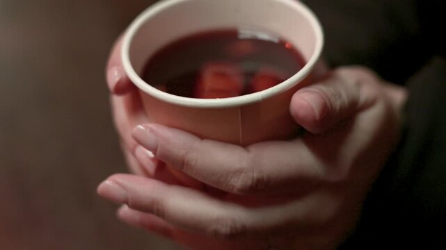 Close Up Hands Holding Hot Mulled Wine Cup in Winter Christmas Market