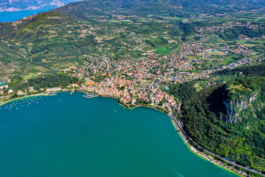Aerial view of the town on the shores of Lake Garda with lush green hills and turquoise water in Italy.