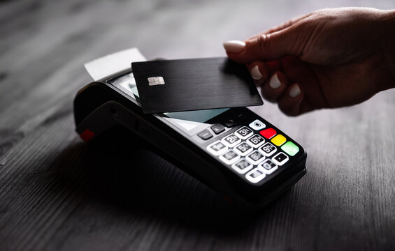 Girl Paying With Credit Card Using Wireless Pos Terminal On A Black Table