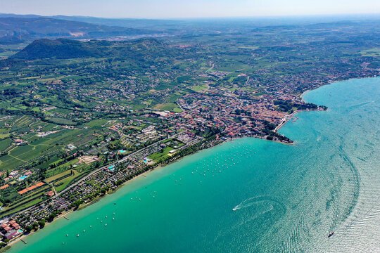 Aerial view of Bardolino on the shores of Lake Garda with turquoise water, boats, and lush green hills in Provincia di Verona, Veneto, Italy.