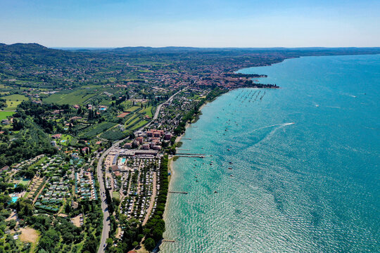 Aerial view of Bardolino on the shores of Lake Garda with turquoise water, lush green hills, and coastal campsites Provincia di Verona, Veneto, Italy.