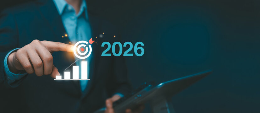 Businessman pointing finger at target icon with year twenty twenty six and growing bar chart graphic representing long term goals and financial forecasting for future success.