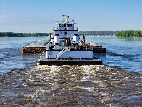 Rear view of a Tug boat pushing a large set of barges South down the Mississippi River