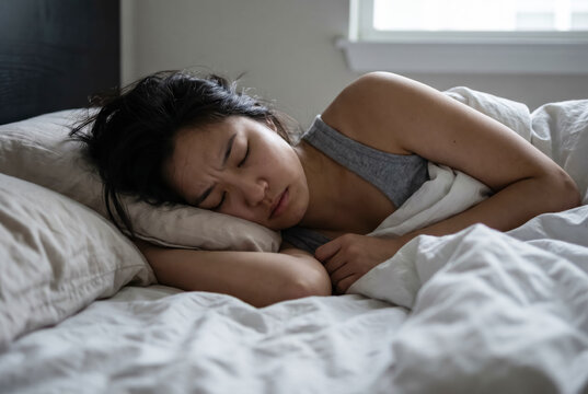 Stressed young Asian woman having a nightmare or sleeping uncomfortably in bed