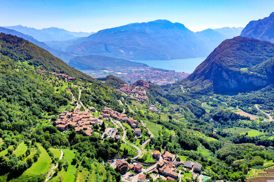 Aerial view of the historic stone village of Canale di Tenno nestled in lush green hills with Lake Garda in the background Ville del Monte, Trentino-Alto Adige, Italy.